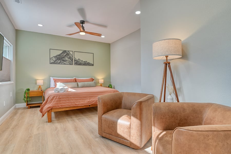 En suite bedroom with king bed, sitting chairs, 50" Smart TV, Walk in closet and stunning bathroom