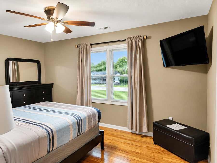 Inviting 2nd bedroom featuring a flat-screen TV and stylish storage dresser