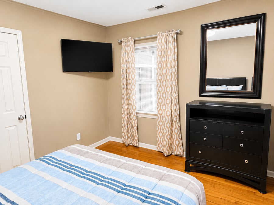 Comfortable bedroom featuring a flat-screen TV and stylish dresser