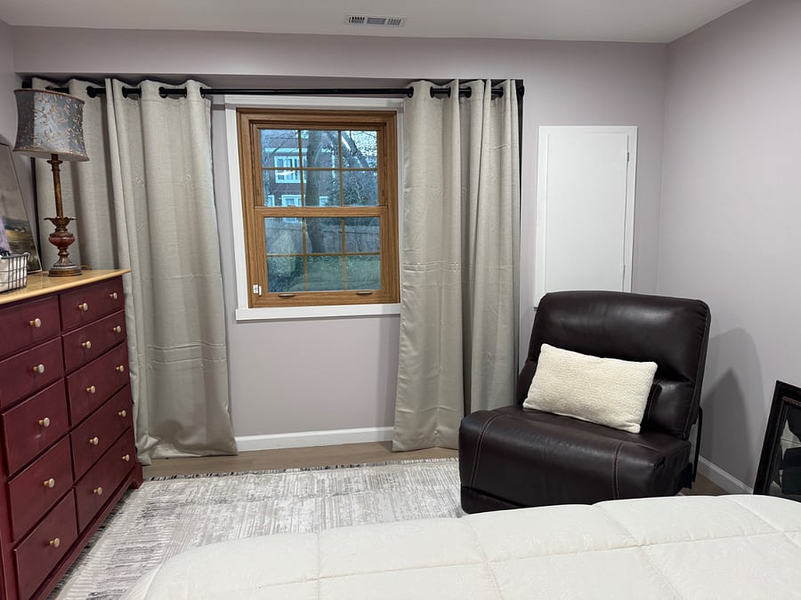Apartments bedroom with queen bed and a window looking out over the mabackyard prettiness.
