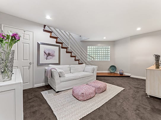 Lower-level bonus family room with sectional, large-format TV, and staircase access.