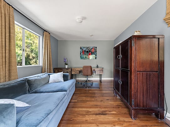 Office configuration with blue velvet sofa, rustic wood desk, and private balcony access.