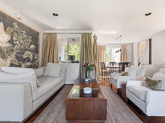 Main-level living room with curated floral mural, sectional seating, and open flow to the dining area.