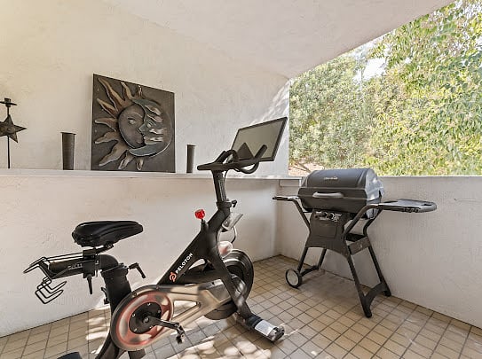 Covered patio off the dining room with Peloton bike, gas BBQ grill, and weather protection.