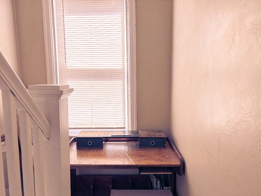 Desk sitting at the base of stairwell leading to closed attic (no access, not remodeled).