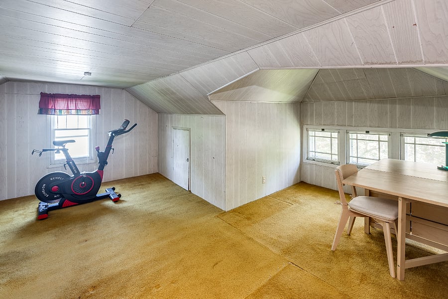 Attic space provides ample storage and includes an exercise bike and crafting table