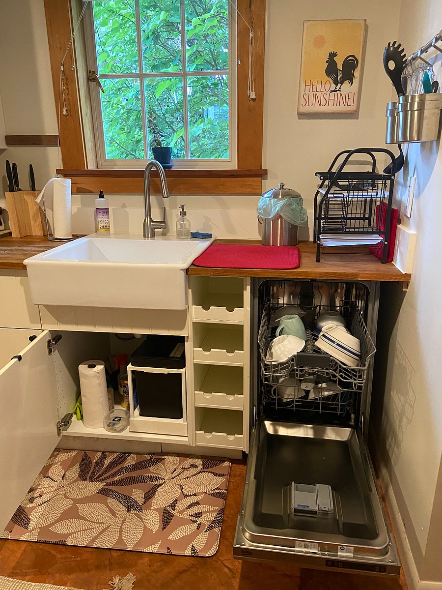 Kitchen: under sink (storage/cleaning supplies), open dishwasher (new 2024), food waste container and wine rack. 