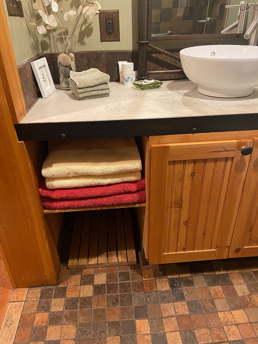 Bathroom wood cabinet. Open shelves for towels, under sink storage for cleaning supplies. 