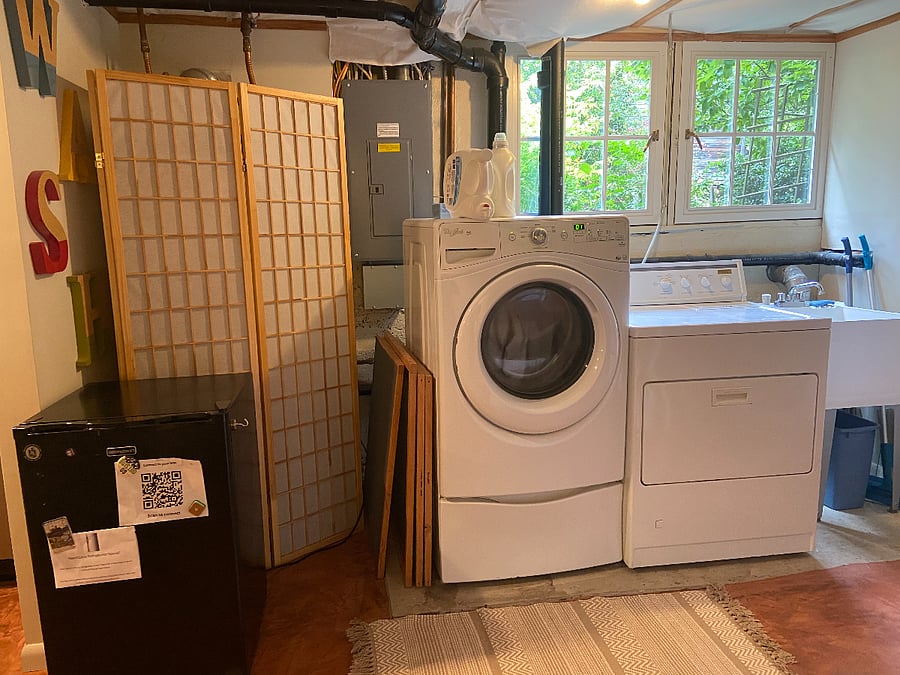 Full size washing machine and dryer (with laundry sink). Screen hides water heater. Quarter wall divides laundry room from kitchen. 