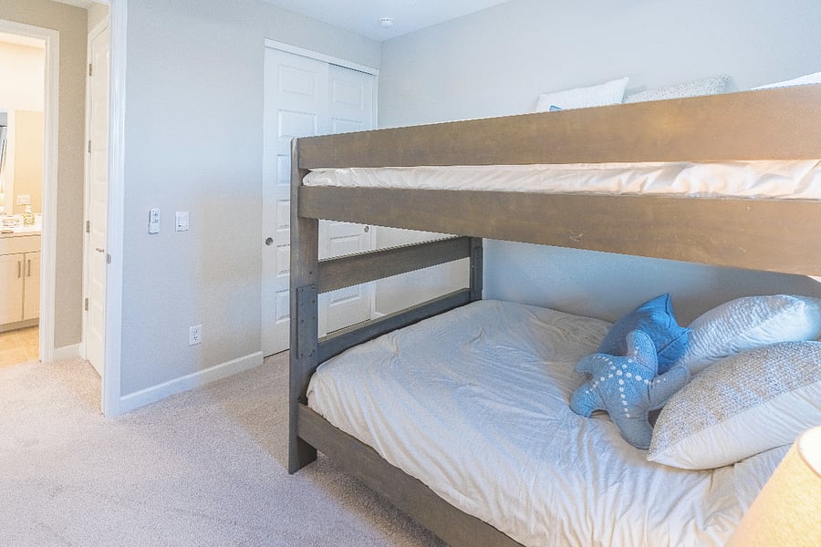 Bright bunk-bed room with spacious layout, soft carpeting, and easy bathroom access.