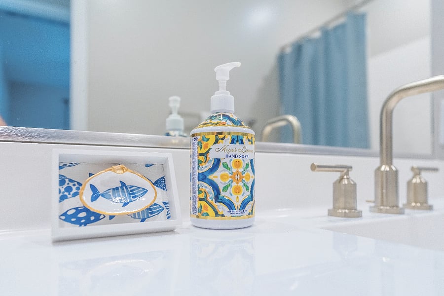 Bright bathroom vanity with gold fixtures and decorative hand soap.