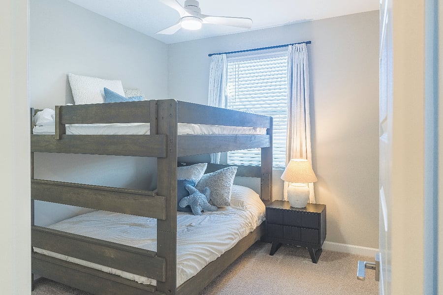 Cozy family-friendly bedroom with sturdy bunk beds, soft bedding, and warm lighting.