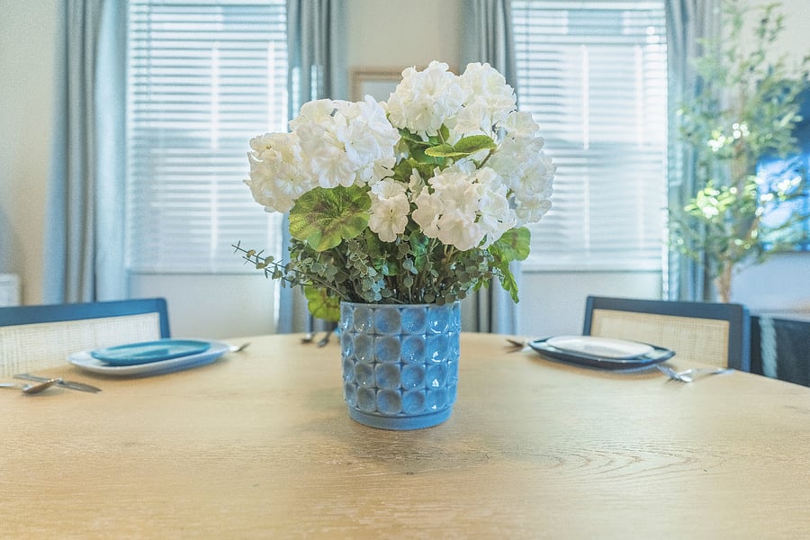 Elegant floral centerpiece on a round wooden dining table adds a fresh, welcoming touch.