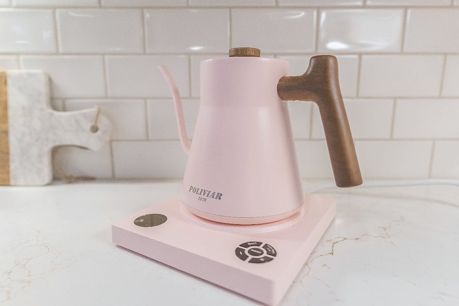 Chic pink goose neck kettle on quartz counters adds a cozy, designer touch to this modern kitchen.