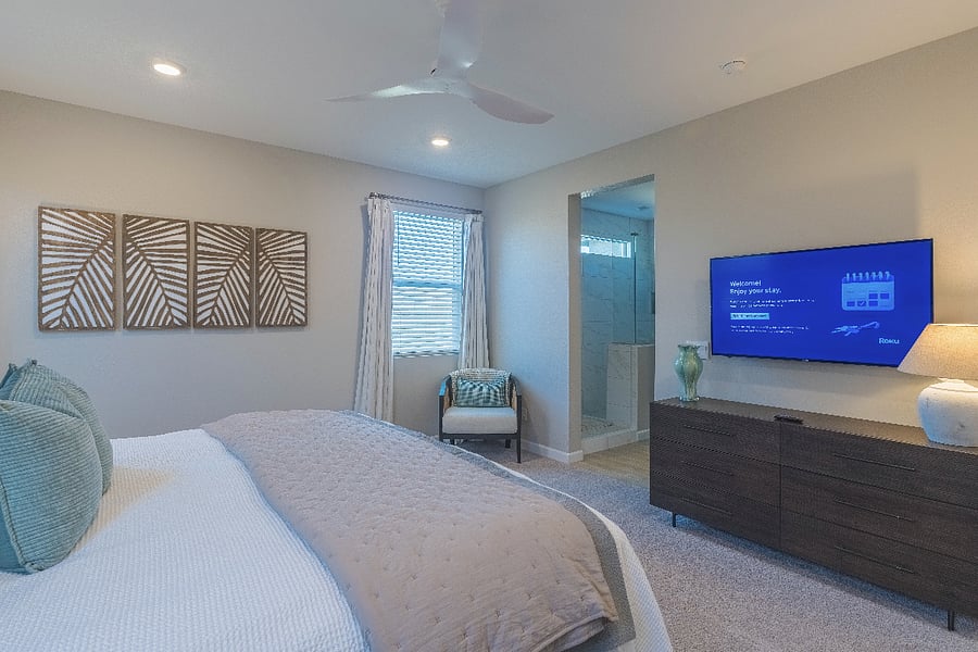 Spacious master suite with mounted Roku TV, modern decor, and private ensuite bathroom.