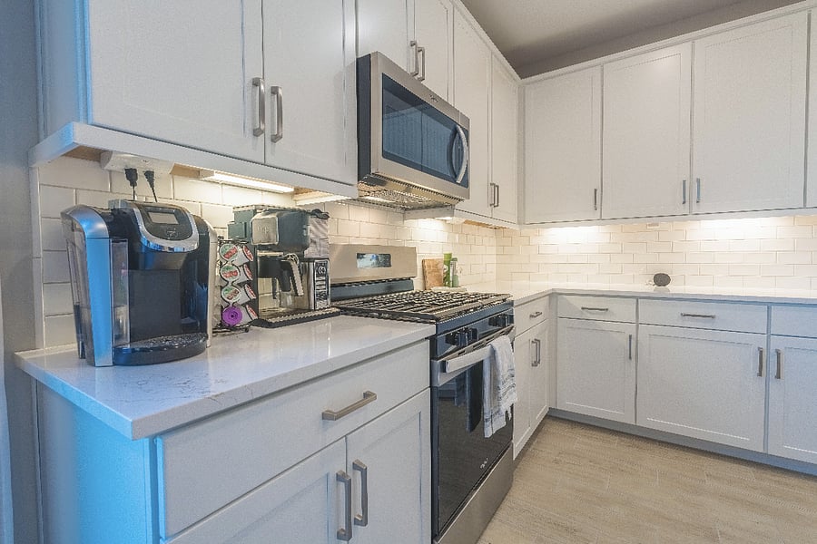 Modern kitchen with stainless steel appliances, quartz countertops, subway tile backsplash, and a fully stocked coffee station.