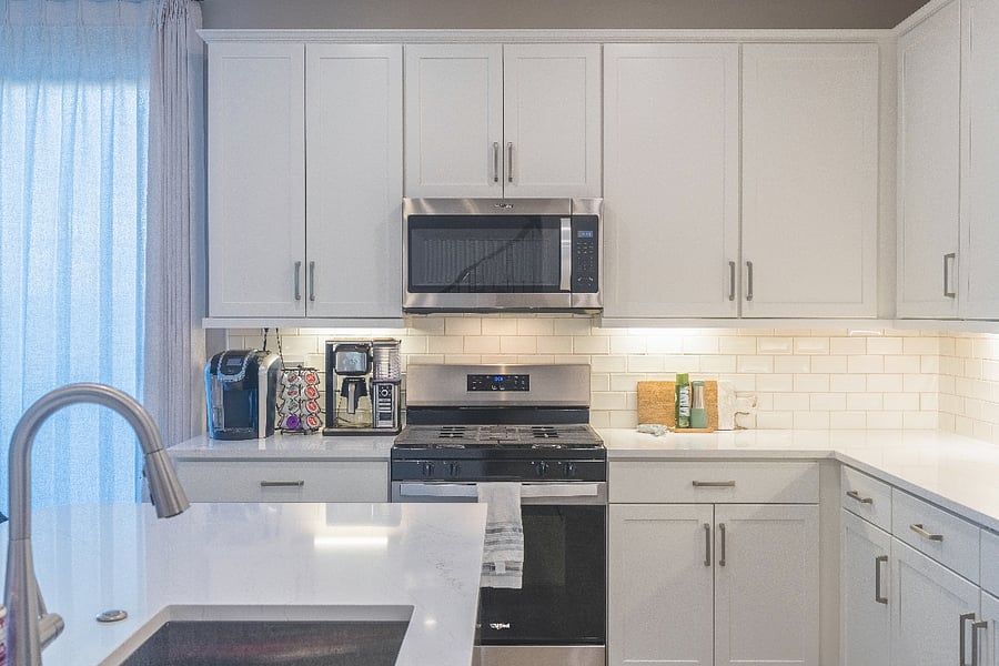 Stylish kitchen with stainless steel appliances, subway tile backsplash, and a fully stocked coffee bar.