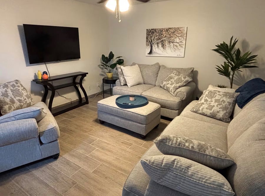 Large family room with oversized comfy couches, beautiful artwork, and smart TV.
