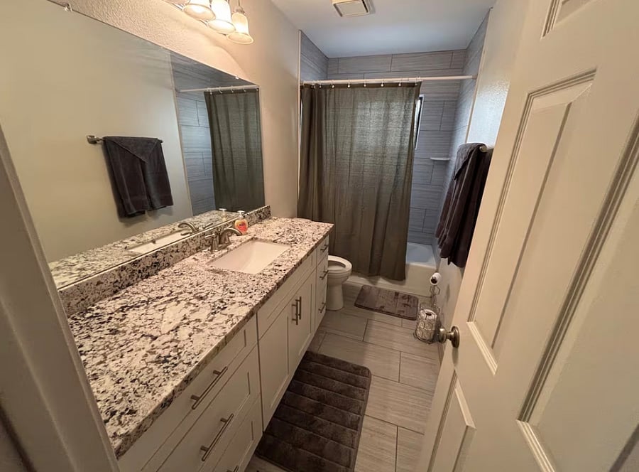 Hall bathroom with storage, and combo tub and shower.