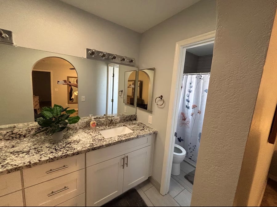 Primary bathroom with dual vanity, storage, and walk-in shower.