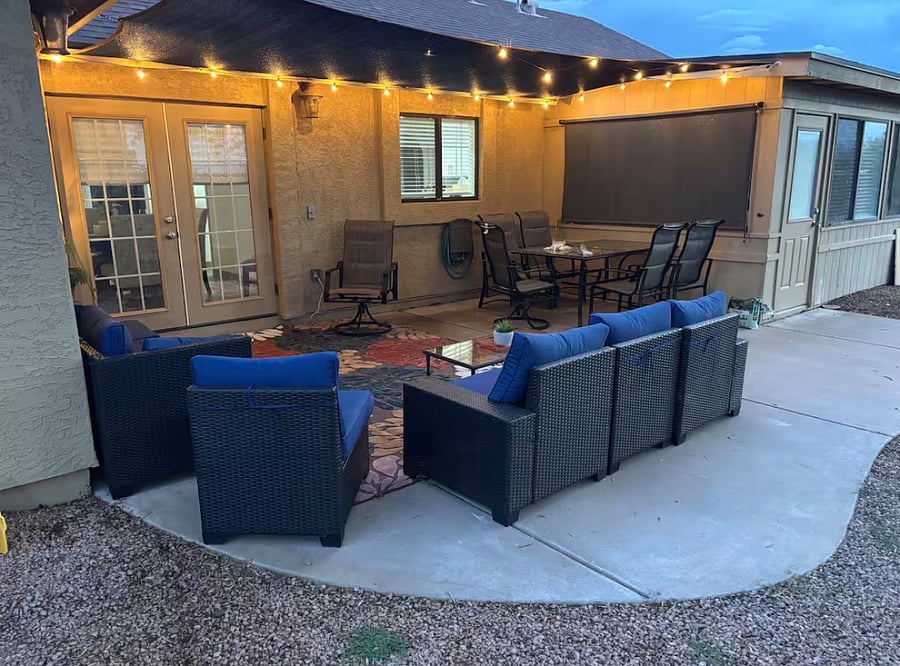 Beautifully furnished, fully fenced backyard with sectional outdoor sofa, dining for 6, outdoor room for activities/games, trees and shrubs, and lighting and shade for enjoying year round, day and night.