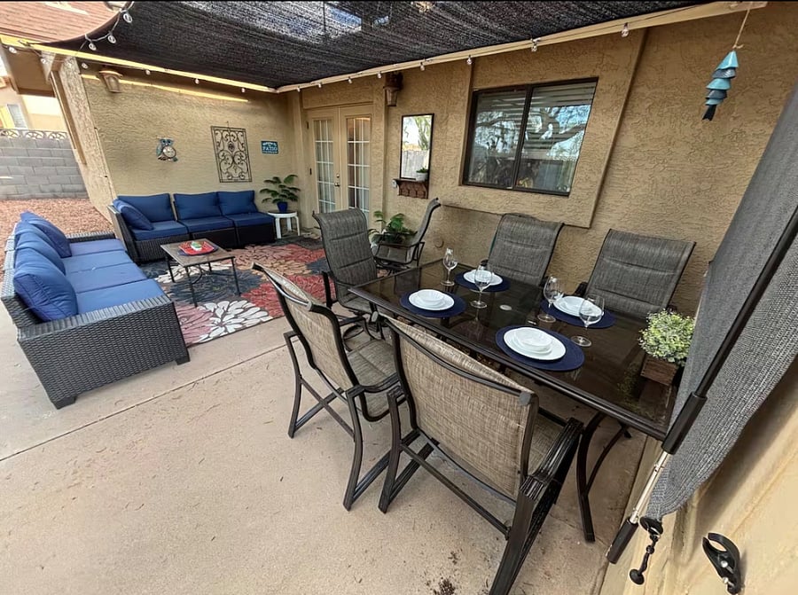 Beautifully furnished, fully fenced backyard with sectional outdoor sofa, dining for 6, outdoor room for activities/games, trees and shrubs, and lighting and shade for enjoying year round, day and night.