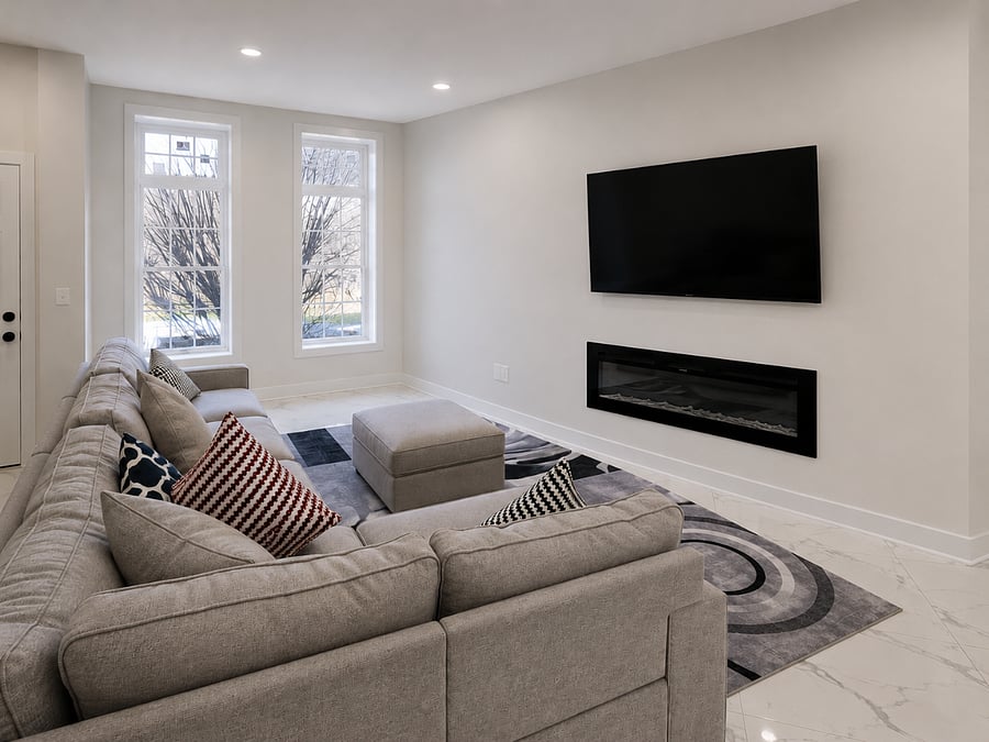 Bright & Modern Living Room
This living area blends comfort and contemporary design, featuring a spacious sectional sofa, elegant marble-look flooring, and abundant natural light from oversized windows. The focal point of the room is a sleek wall-mounted electric fireplace paired with a large flat-screen TV, creating the perfect space for relaxing or entertaining. Neutral tones, recessed lighting, and clean architectural lines give the room a bright, open feel, while the open-concept layout seamlessly connects to the rest of the home. Stylish, modern, and thoughtfully designed, this living space offers both sophistication and everyday comfort.