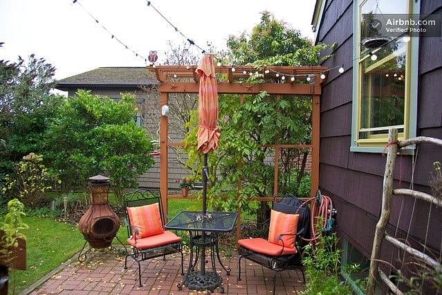 Backyard with patio lights, fire pit, and gas stainless Weber grill.